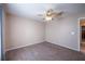 A carpeted bedroom with neutral walls and fan is adjacent to another room at 31028 Baclan Dr, Wesley Chapel, FL 33545