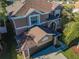A partial elevated view of a two-story brown home, garage and driveway with palm trees in the yard at 31028 Baclan Dr, Wesley Chapel, FL 33545
