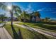 Landscaped front yard and sidewalk leading to a 2-story home with palm trees and blue skies at 31028 Baclan Dr, Wesley Chapel, FL 33545