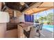 Outdoor kitchen area with bar seating, a stone counter, and an outdoor hood at 31028 Baclan Dr, Wesley Chapel, FL 33545