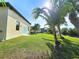 Wide shot of backyard with lawn and landscaping as well as home with pool in background at 3215 Peace River Dr, Punta Gorda, FL 33983