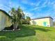 Well-maintained backyard with lush green lawn, palm trees, and a detached garage with a vibrant turquoise door at 3215 Peace River Dr, Punta Gorda, FL 33983