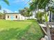 The backyard features a lush lawn, some tropical landscaping and a building with cute blue doors at 3215 Peace River Dr, Punta Gorda, FL 33983