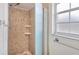 A tiled shower features an adjustable shower head, two shelves, and a textured sliding door at 3803 Pin Oaks St, Sarasota, FL 34232