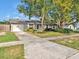 Single-story home featuring a well-manicured lawn, mature trees, and a driveway leading to an attached garage at 909 Kirkcaldy Way, Valrico, FL 33594