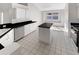 Well-lit kitchen features white cabinets, black countertops, an island, white tile floors and stainless-steel appliances at 11823 Derbyshire Dr, Tampa, FL 33626