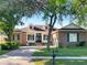 Charming brick home features a manicured lawn, blue shutters and a brick-paved driveway and walkway at 2317 Valrico Forest Dr, Valrico, FL 33594