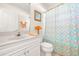 Well-lit bathroom featuring a vanity, toilet, and shower-tub combo with a colorful curtain at 3699 N Chamberlain Blvd, North Port, FL 34286