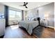 Bedroom features stylish grey decor, a ceiling fan, a large window, and wood flooring at 11826 Sky Acres Ter, Bradenton, FL 34211