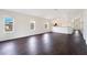 Bright living area with sleek flooring, three windows, and access to a kitchen at 13202 Golf Ridge Pl, Hudson, FL 34669