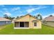 Home's rear exterior featuring a screened-in patio, a window, and a well-manicured lawn at 13202 Golf Ridge Pl, Hudson, FL 34669