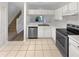 Kitchen with stainless steel dishwasher, sink, stove, white cabinets and view to a staircase at 1238 Standridge Dr, Wesley Chapel, FL 33543