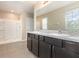 Bathroom featuring double sinks, dark wood cabinets and shower with white tile surround at 11807 Myrtle Rock Dr, Riverview, FL 33578