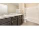 Bright bathroom featuring double sinks, dark wood cabinets and shower with white tile surround at 11807 Myrtle Rock Dr, Riverview, FL 33578
