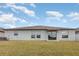 A backyard of the home featuring a lush green lawn, large sliding glass doors and a covered patio area at 13581 Willow Bluestar Loop, Riverview, FL 33579