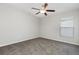 This bedroom features gray carpet, a ceiling fan with light, and a window providing natural light at 13581 Willow Bluestar Loop, Riverview, FL 33579