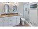 Bathroom featuring double sink vanity with granite countertops and tiled shower with glass doors at 1404 Rosewood Ave, Dunedin, FL 34698