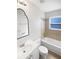 Bright bathroom featuring a vanity, toilet, and tiled shower-tub combination with a window at 1404 Rosewood Ave, Dunedin, FL 34698