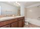 Bathroom with dual sinks, a bathtub-shower, tile flooring, and warm-toned cabinetry, blending function with elegance at 13417 Lake Monroe Pl, Riverview, FL 33579
