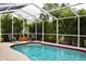 Sparkling pool inside a screened enclosure offers relaxation and privacy with tropical landscaping at 26187 Argentina Dr, Punta Gorda, FL 33983