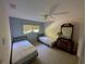 Neutral bedroom featuring two beds, a ceiling fan, and window overlooking a leafy yard at 5701 Ainsworth W Ct, Tampa, FL 33647