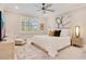 Bright bedroom featuring a neutral color palette, ceiling fan, and seating area near window at 10735 Spring Tide Way, Parrish, FL 34219