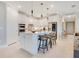 Modern white kitchen with stainless steel appliances, a center island, and stylish pendant lighting at 10735 Spring Tide Way, Parrish, FL 34219