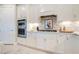 Contemporary white kitchen featuring stainless steel appliances, stylish backsplash, and ample cabinet space at 10735 Spring Tide Way, Parrish, FL 34219
