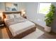 Bedroom with neutral color palette, wooden bed frame, large windows, and a decorative tree at 3092 Crowder St, Port Charlotte, FL 33980
