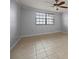A clean and bright bedroom showcasing neutral walls, tile flooring, and a large window at 14810 Rue De Bayonne # 7B, Clearwater, FL 33762