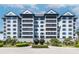 Stunning exterior of a multi-story white condo building with lush landscaping and a circular driveway leading to a covered entrance at 14810 Rue De Bayonne # 7B, Clearwater, FL 33762