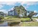 Exterior view of a building, green lawns, and a scenic pond under a sunny sky at 14810 Rue De Bayonne # 7B, Clearwater, FL 33762