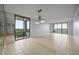 Spacious empty room featuring neutral tile flooring, glass door to balcony, mirrored wall, and vintage chandelier at 14810 Rue De Bayonne # 7B, Clearwater, FL 33762