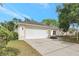 Attached two-car garage, white door and frame, neutral exterior color, lush landscaping, on a sunny day at 11019 Pine Lilly Pl, Lakewood Ranch, FL 34202