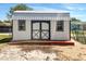 A white shed with black trim features a metal roof, small windows, and a wood ramp at 1115 31St W St, Bradenton, FL 34205