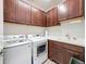 Well-equipped laundry room with dark cabinets, sink, and modern washer and dryer at 18743 Coastal Shore Ter, Land O Lakes, FL 34638