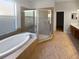 Bathroom features a tub, glass enclosed shower, and neutral colored tile at 4249 Hawksley Pl, Wesley Chapel, FL 33545