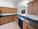 Well-lit kitchen featuring granite countertops, wood cabinets, stainless steel dishwasher, and tiled floors at 4249 Hawksley Pl, Wesley Chapel, FL 33545