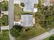 Aerial view of a home with gray roof, green lawn, driveway, and mature trees on a sunny day at 2436 Deer Trail Ln, Spring Hill, FL 34606