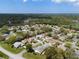 A wide aerial view showing a neighborhood nestled within a lush green landscape under a blue sky at 2436 Deer Trail Ln, Spring Hill, FL 34606