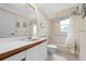 Bathroom featuring a vanity with a sink, toilet, and a shower-tub combo with seashell wallpaper at 2436 Deer Trail Ln, Spring Hill, FL 34606