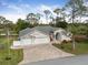 An elevated view of a single-story home boasting a lush lawn, brick driveway, and an attached two-car garage at 2444 Grandfather Mtn, Spring Hill, FL 34606