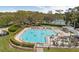 Aerial view of a large, rectangular community pool surrounded by lounge chairs, lush greenery, and palm trees at 2444 Grandfather Mtn, Spring Hill, FL 34606