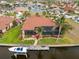 Aerial view of a waterfront home features dock, boat lift, screened lanai, and tropical landscaping under a bright blue sky at 3629 Licata Ct, Punta Gorda, FL 33950