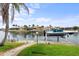 Dock with boat lift showcasing a waterfront home, green lawn, and well-maintained landscaping under a bright sky at 3629 Licata Ct, Punta Gorda, FL 33950