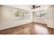 Sun-filled bedroom featuring wood floors, ceiling fan, and two windows overlooking the backyard at 3702 Pensdale Dr, New Port Richey, FL 34652