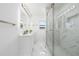 All-white bathroom with a double sink vanity, patterned tile floor, and glass-enclosed shower at 520 Baywood S Dr, Dunedin, FL 34698