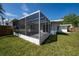 Rear view of the home highlights the screened patio and well manicured lawn at 520 Baywood S Dr, Dunedin, FL 34698