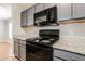 Galley kitchen featuring stone countertops, gray cabinets and stainless steel appliances at 13516 Copper Head Dr, Riverview, FL 33569