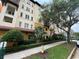 Multi-story building featuring a red tile roof, lush landscaping, and a sidewalk with trees at 200 4Th S Ave # 231, St Petersburg, FL 33701